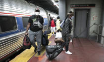 Travelers arriving on a train that originated in Miami carry their luggage at Amtrak's Penn Station, Thursday, Aug. 6, 2020, in New York. Mayor Bill de Blasio is asking travelers from 34 states, including Florida where COVID-19 infection rates are high, to quarantine for 14 days after arriving in the city. (AP Photo/Mark Lennihan)