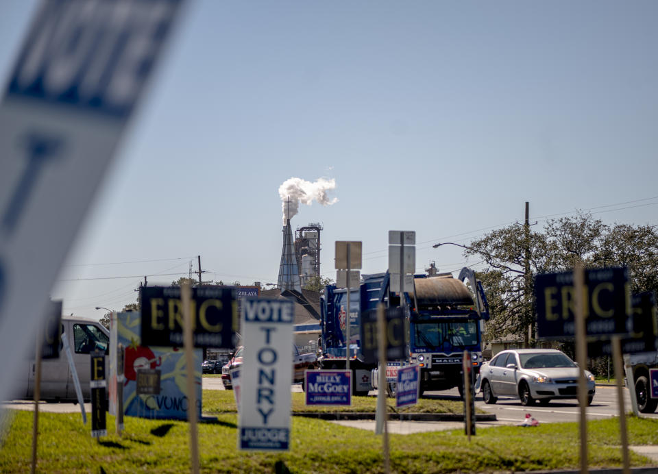 Voting signs on a lawn near an intersection.