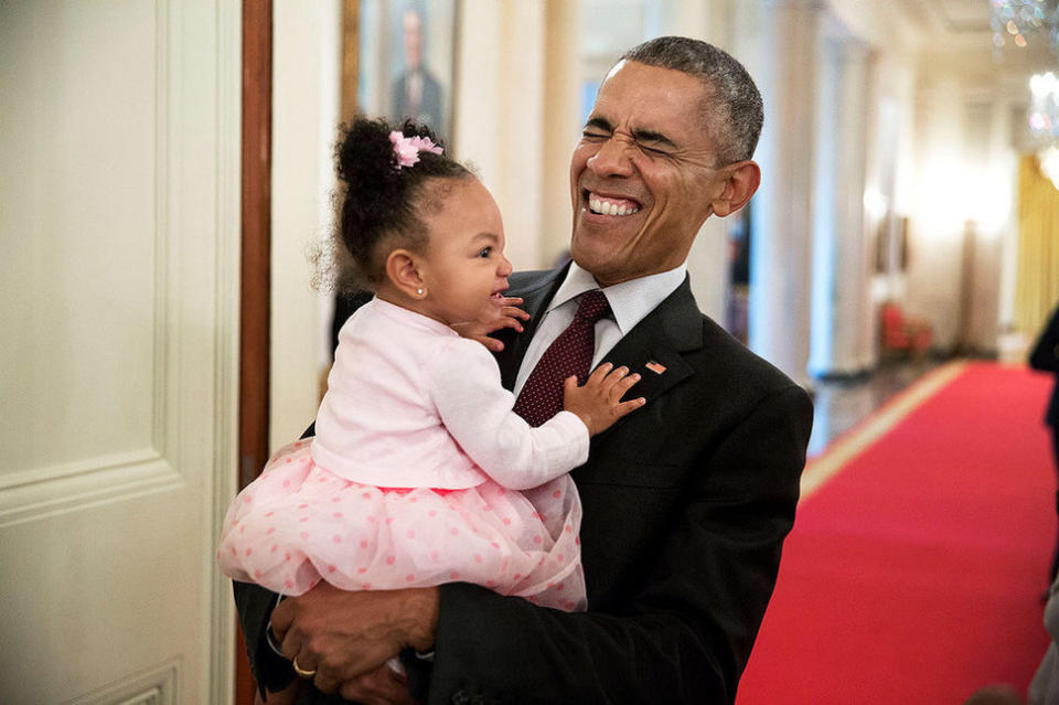 President Barack Obama holds the daughter of former staff member Darienne Page Rakestraw in the Cross Hall of the White House on April 3, 2015.