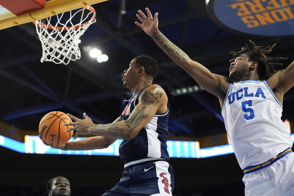Arizona forward Keshad Johnson, left, drives to the basket past UCLA guard Brandon Williams during the first half of an NCAA college basketball game in Los Angeles, Thursday, March 7, 2024. (AP Photo/Jae C. Hong)