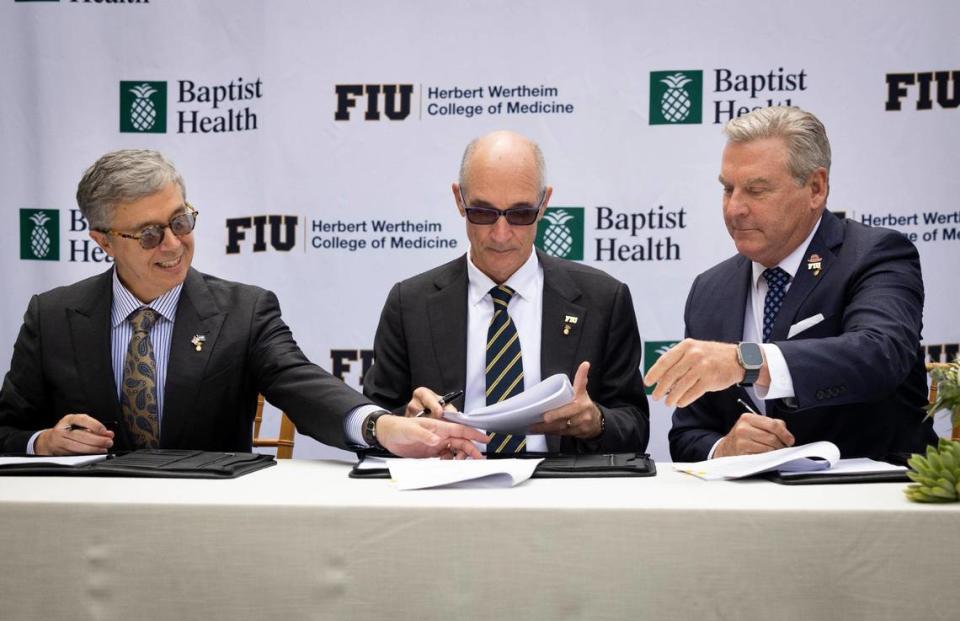 Juan Cendan, Dean of the Herbert Wertheim College of Medicine at FIU, left; Kenneth Jessell, FIU president, center; and Bo Boulenger, CEO of Baptist Health South Florida, sign papers during a ceremony for the clinical and academic partnership between Baptist Health and Florida International University on Tuesday, Nov. 28, 2023, at Baptist Health Miami Cancer Institute.