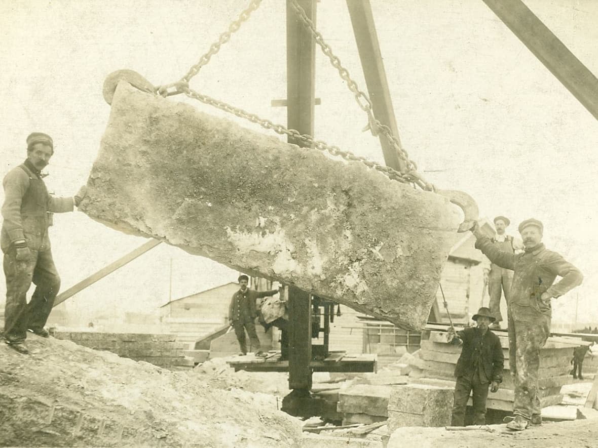 August Gillis, founder of Gillis Quarries, is in the foreground at the right of a slab of Tyndall Stone in this undated photo.  (Supplied by Gillis Quarries - image credit)