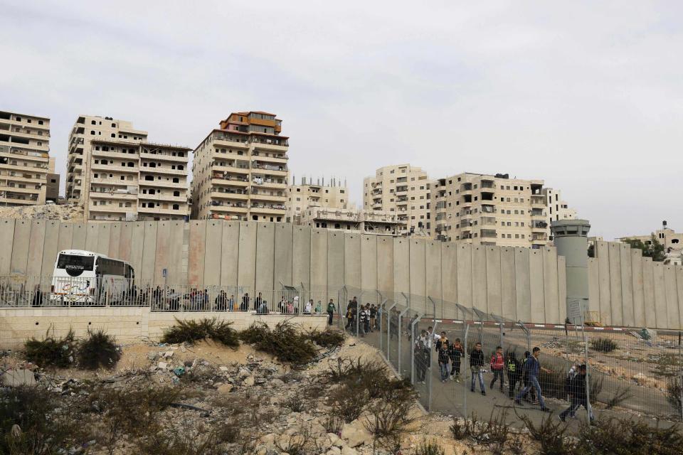 Palestinian children disembark their school bus and walk towards an Israeli checkpoint in East Jerusalem