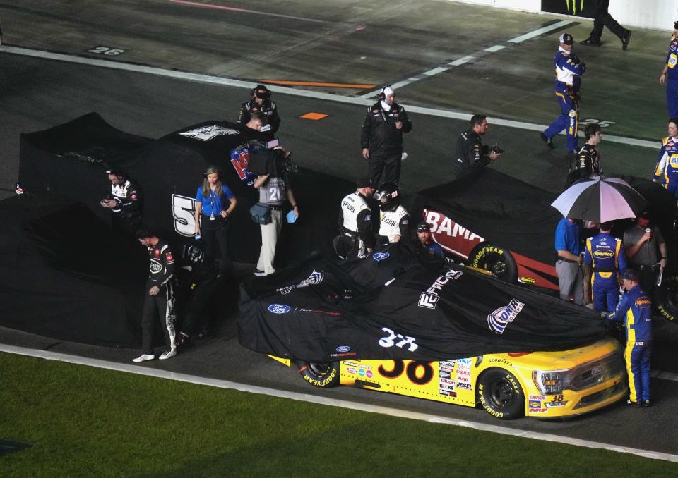 Covers are put on the trucks, including leader Zane Smith (38), as rain brings out the second red flag with 27 laps to go in the NextEra Energy 250 on Friday at Daytona International Speedway.