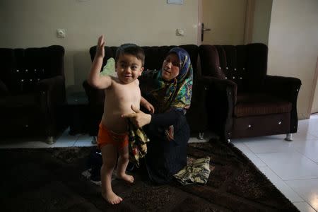 Two-year-old Emad's mother, Zahra Khorasani helps him get changed at their relative's home in south of Tehran, Iran, June 18, 2017. Nazanin Tabatabaee Yazdi / TIMA via REUTERS