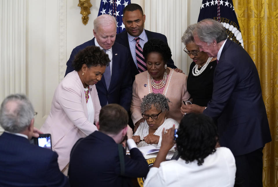 People take photos as Opal Lee holds a pen and is seated where President Joe Biden signed the Juneteenth National Independence Day Act, in the East Room of the White House, Thursday, June 17, 2021, in Washington. (AP Photo/Evan Vucci)