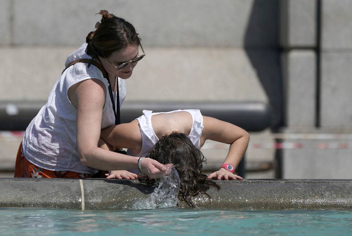 A person wets their hair in a fountain at Trafalgar Square in central London, Tuesday July 19, 2022. Millions of people in Britain woke from the country’s warmest-ever night on Tuesday and braced for a day when temperatures could break records, as a heat wave scorching Europe walloped a country not built for such extremes (Aaron Chown/PA via AP)