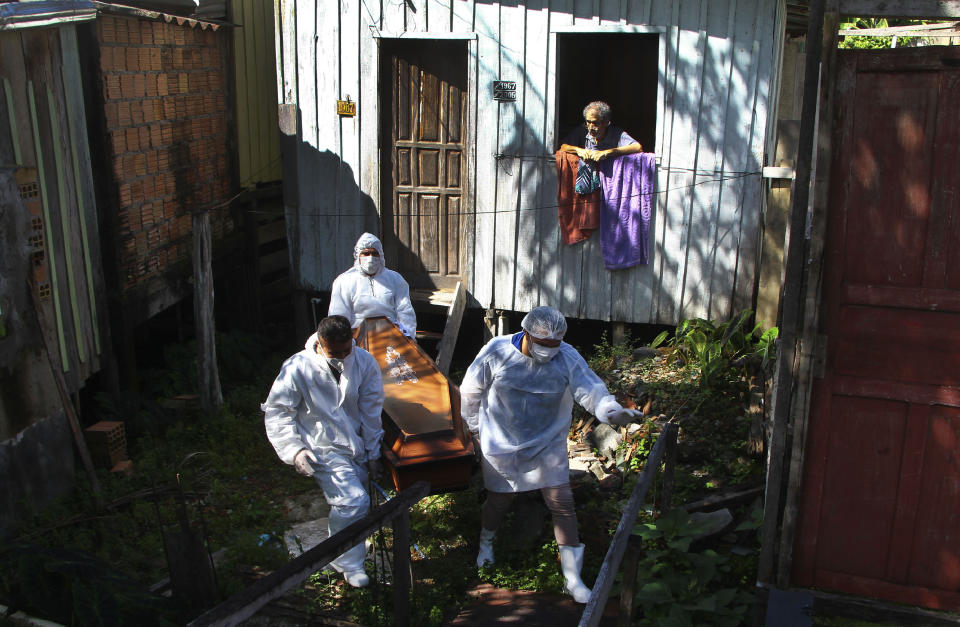 FILE - In this Jan. 22, 2021, file photo, family member watches as public funeral service workers remove the body of Amelia Dias Nascimento, 94, who died from complications related to COVID-19 in her home, in Manaus, Amazonas state. Brazil’s COVID-19 death toll, at nearly 250,000 on Thursday, Feb. 25, is the world’s second-highest for the same reason its second wave has yet to fade: Prevention was never made a priority. (AP Photo/Edmar Barros, File)