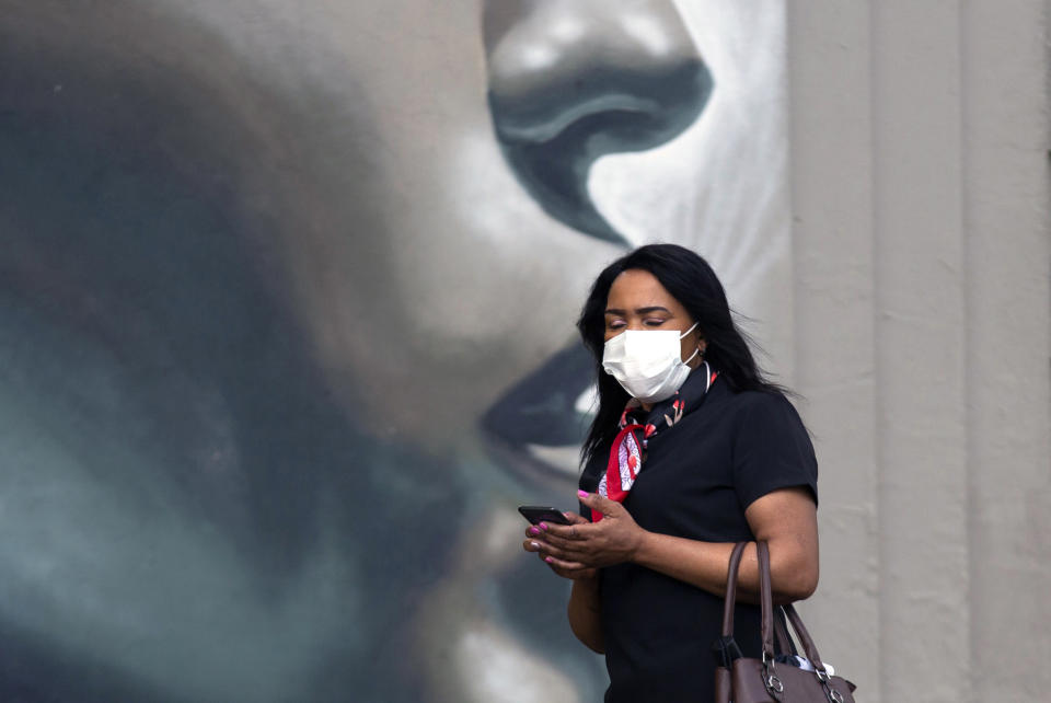 A pedestrian wearing a mask to protect against COVID-19 passes a wall mural on a sidewalk in Johannesburg, Wednesday, Feb. 24, 2021. In Finance Minister's budget speech in Parliament, Tito Mboweni said South Africa plans to spend dollars 712 million to vaccinate some 67% of its 60 million people to control the country's COVID-19 battle and get the economy to rebound from its decline of 7.2% last year. (AP Photo/Denis Farrell)