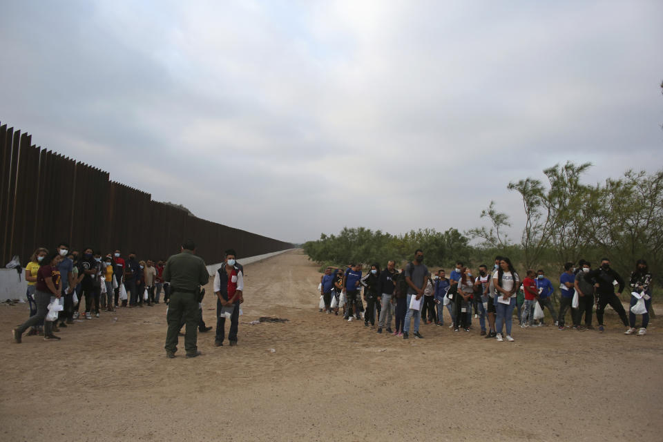 A Border Patrol agent instructs migrants who had crossed the Rio Grande river into the U.S. in Eagle Pass, Texas, Friday, May 20, 2022. As U.S. officials anxiously waited, many of the migrants crossing the border from Mexico on Friday were oblivious to a pending momentous court ruling on whether to maintain pandemic-related powers that deny a chance to seek asylum on grounds of preventing the spread of COVID-19. (AP Photo/Dario Lopez-Mills)