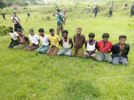 Ten Rohingya men with their hands bound kneel as members of the Myanmar security forces stand guard in Inn Din village of Rakhine State, Myanmar, September 2, 2017. Handout via REUTERS