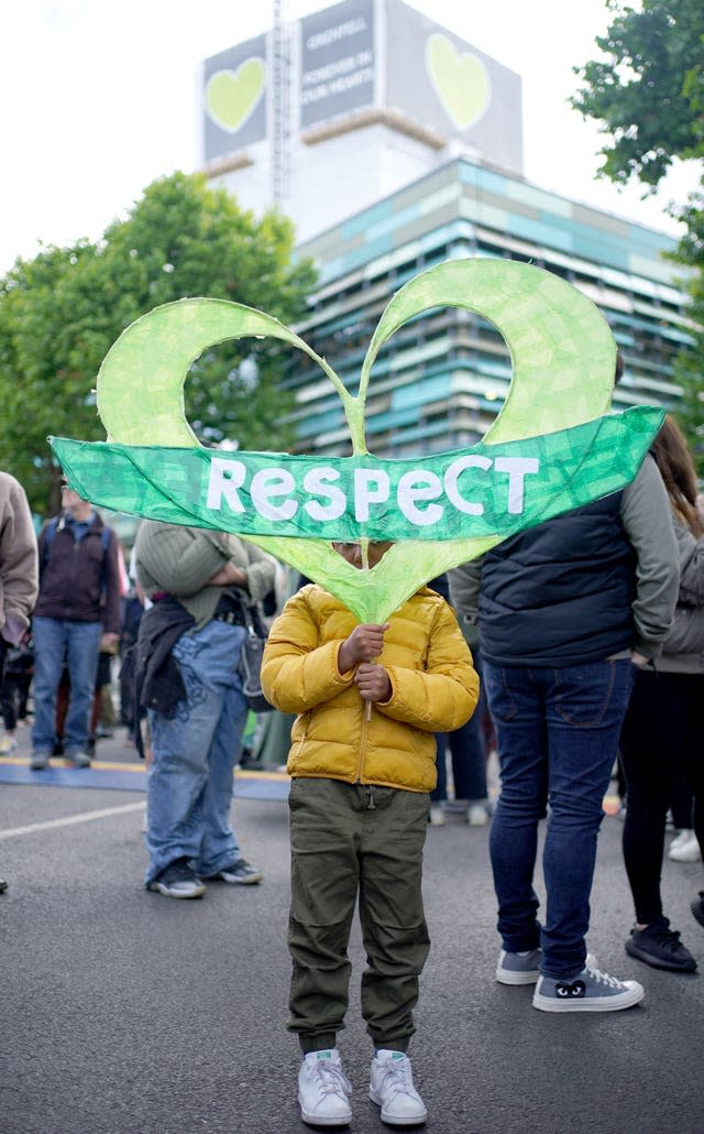 A young boy holds a sign saying Respect in front of Grenfell Tower