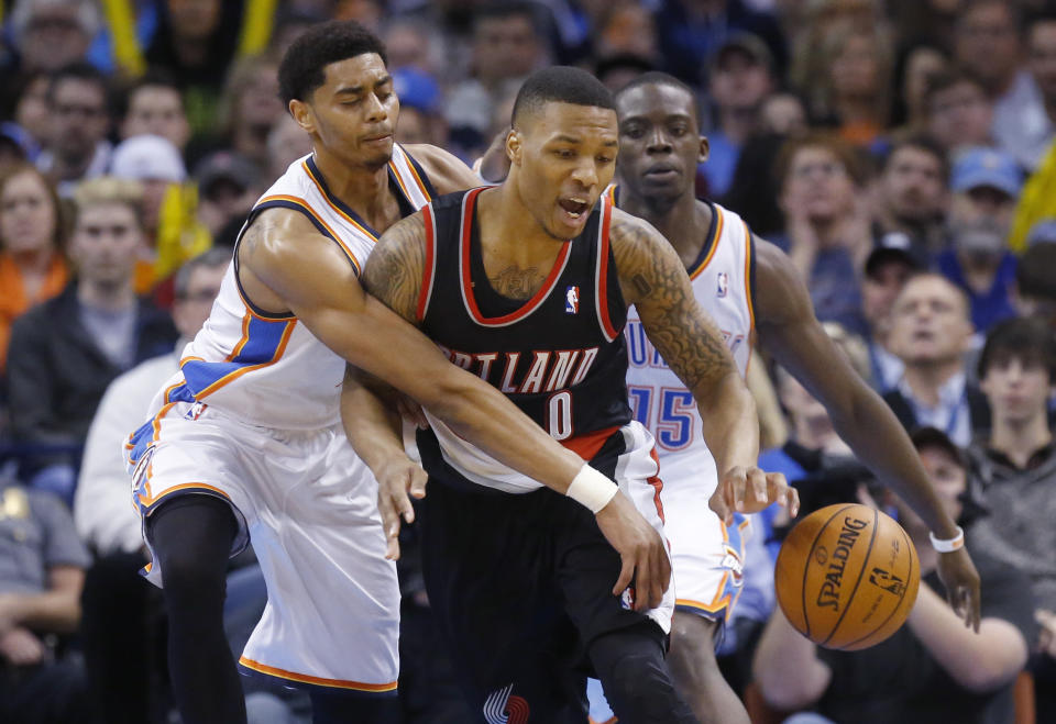 Oklahoma City Thunder guard Jeremy Lamb, left, knocks the ball away from Portland Trail Blazers guard Damian Lillard (0) in the fourth quarter of an NBA basketball game in Oklahoma City, Tuesday, Jan. 21, 2014. Oklahoma City won 105-97. Thunder guard Reggie Jackson (15) is at right. (AP Photo/Sue Ogrocki)