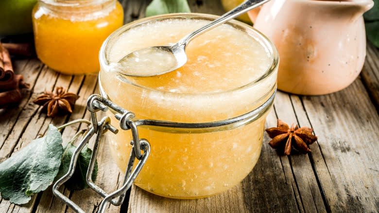 Opened glass jar of applesauce with spoon