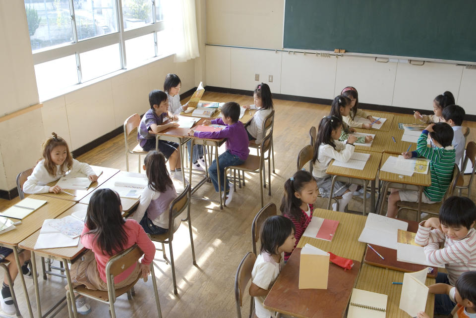 Teacher and students engaging in a classroom activity at desks