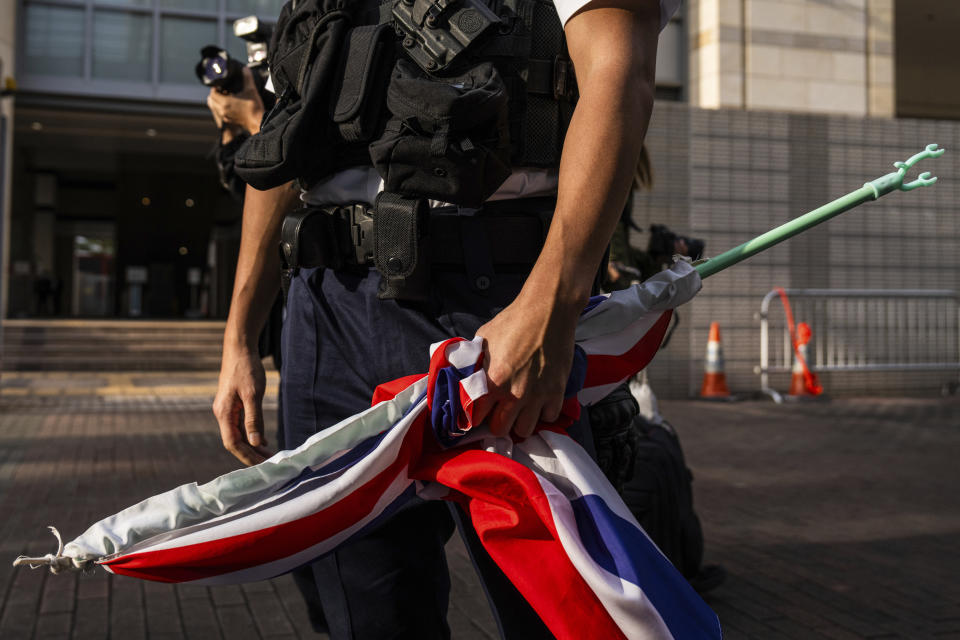 A police officer holds a British flag brought by a pro-democracy activist known as "Grandma Wong," outside the West Kowloon courts as closing arguments open in Hong Kong's largest national security trial of 47 pro-democracy figures in Hong Kong, Wednesday, Nov. 29, 2023. (AP Photo/Louise Delmotte)