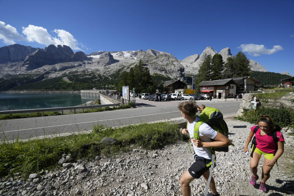 Hikers walk past the Marmolada mountain and the Punta Rocca glacier near Canazei, in the Italian Alps in northern Italy, Wednesday, July 6, 2022, where an avalanche broke loose on Sunday, sending tons of ice, snow, and rocks onto hikers. (AP Photo/Luca Bruno)