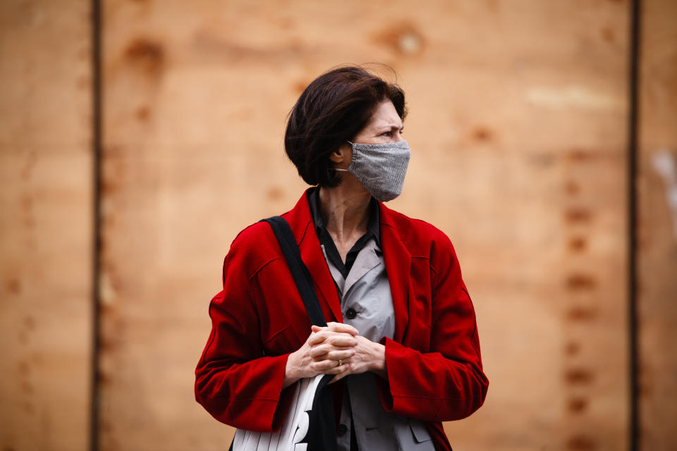 A woman wearing a face mask waits at a pedestrian crossing on Regent Street in London, England, on November 6, 2020. England yesterday began its second national coronavirus lockdown, announced by British Prime Minister Boris Johnson last Saturday, citing fears that covid-19 again threatened to overwhelm the National Health Service (NHS). Pubs, bars, restaurants and non-essential shops are all required to be closed until the currently scheduled end date of December 2. People have meanwhile been asked to stay home as much as possible, although schools and other educational institutions are this time being being kept open and the streets of central London today were markedly busier than the early days of the first lockdown in the spring. (Photo by David Cliff/NurPhoto via Getty Images)