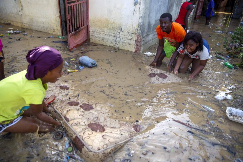 Neighbors help Lafaille Katia, left, pick up a mattress at her flooded house the day after the passing of Tropical Storm Laura in Port-au-Prince, Haiti, Monday, Aug. 24, 2020. Forecasters fear Laura could become a major hurricane along the U.S. Gulf Coast. (AP Photo/Dieu Nalio Chery)