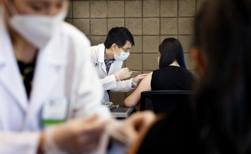 CARSON-CA-SEPTEMBER 16, 2021: Sarith Mey, center left, a pharmacist graduated intern with Rite Aid, administers a shot to CSUDH student Fritzi Bui, 29, during the final of two pop-up COVID-19 vaccination clinics hosted by Cal State Dominguez Hills and Rite Aid for CSUDH students, faculty, staff and community members on campus in Carson on Thursday, September 16, 2021. (Christina House / Los Angeles Times)