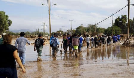 Locals cross a flooded river at Copiapo city, March 26, 2015. REUTERS/Ivan Alvarado