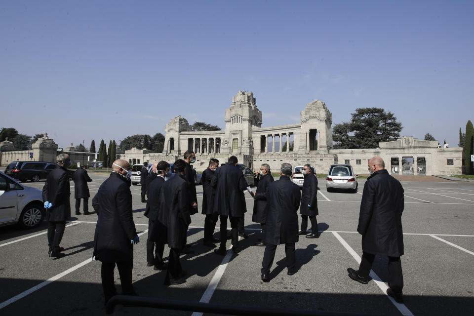 FILE - In this Tuesday, March 17, 2020 file photo, pallbearers stand outside the Monumentale cemetery, in Bergamo, the heart of the hardest-hit province in Italy’s hardest-hit region of Lombardy, Italy. For most people, the new coronavirus causes only mild or moderate symptoms. For some it can cause more severe illness, especially in older adults and people with existing health problems. (AP Photo/Luca Bruno, File)