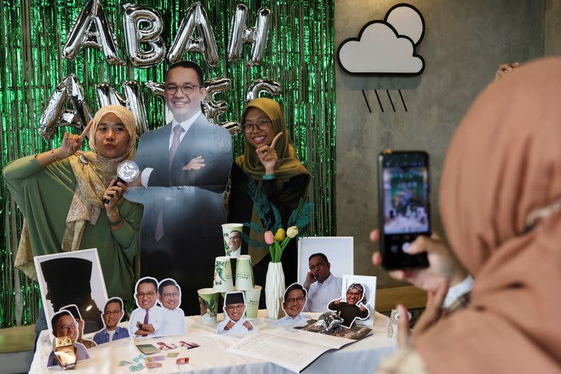 Women pose for a photograph with a cutout depicting Presidential candidate Anies Baswedan during the Humanies Cup Sleeve Event at the Kopi Nako cafe in Jakarta