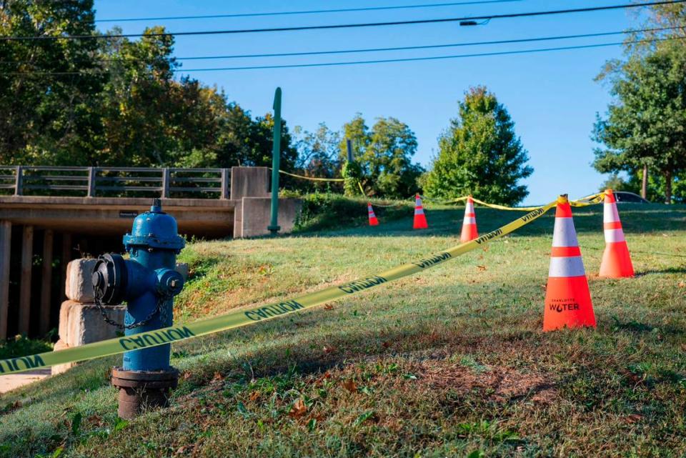 Caution tape and cones from the City of Charlotte’s water department close off a portion of the area surrounding the site of a water main break on Tuesday, October 19, 2021 in Charlotte, NC. On Monday, water was seen gushing from this area under the bridge in the 1400 block of Remount Road.