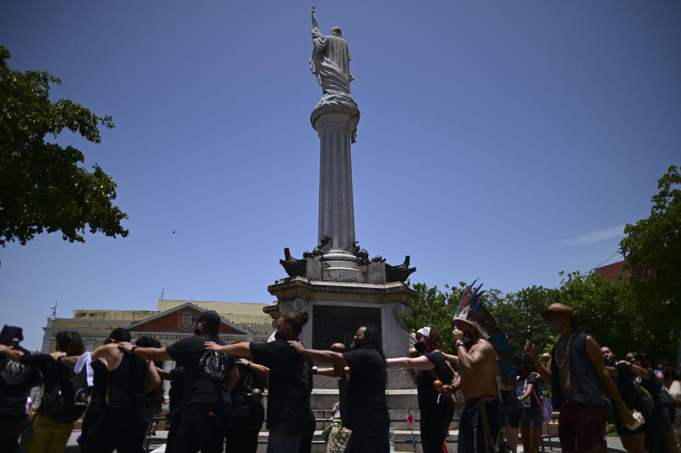 A group of activists surround a monument to Christopher Columbus demanding statues and street names commemorating symbols of colonial oppression be removed, in San Juan, Puerto Rico, Saturday, July 11, 2020. Dozens of activists marched through the historic part of Puerto Rico’s capital on Saturday to demand that the U.S. territory’s government start by removing statues, including those of explorer Christopher Columbus. (AP Photo/Carlos Giusti)