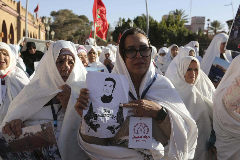 A woman holds photo of a detained activist during a protest against a government plan to change the management of drinking water, in the oasis of Figuig, eastern Morocco, Friday, March 8, 2024. Regional leaders in Morocco met Thursday, March 21, 2024 with residents of an oasis where many have staged protests over a water management plan. Thousands in the eastern Moroccan town of Figuig have demonstrated against their municipal council’s plan to to transition drinking water management to a regional multi-service agency. (AP Photo)