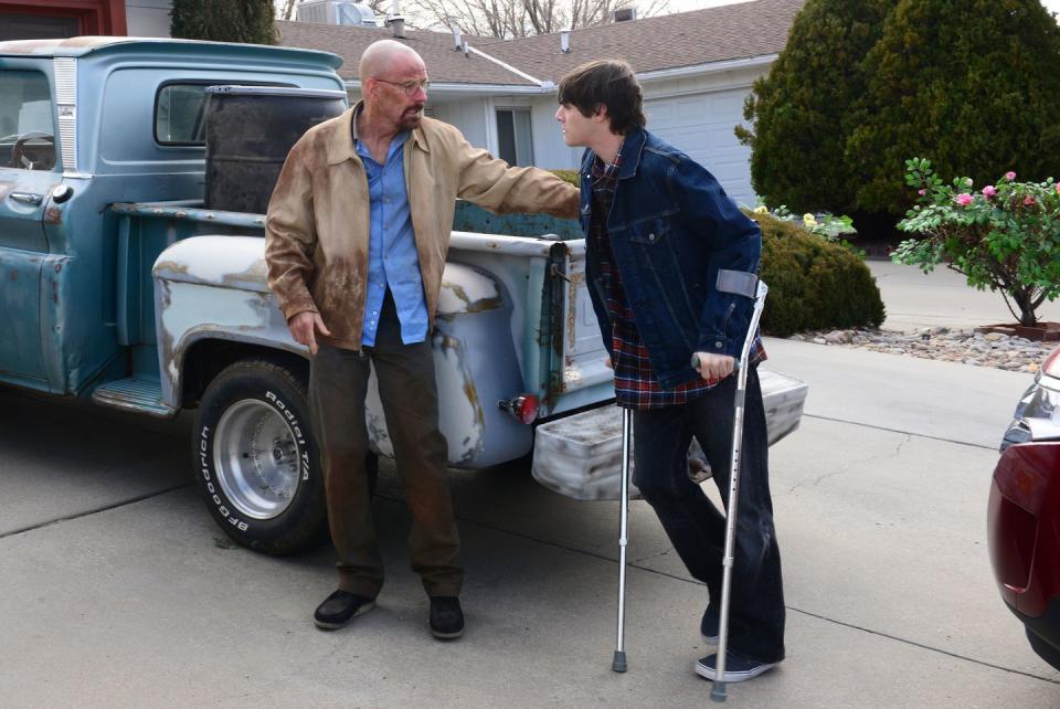 a man and a boy with crutches in front of a truck