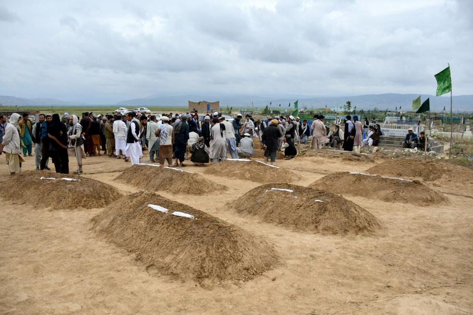 Afghan relatives offer prayers during a burial ceremony, near the graves of victims who lost their lives following flash floods after heavy rainfall at a village in Baghlan-e-Markazi district of Baghlan province on May 11, 2024.