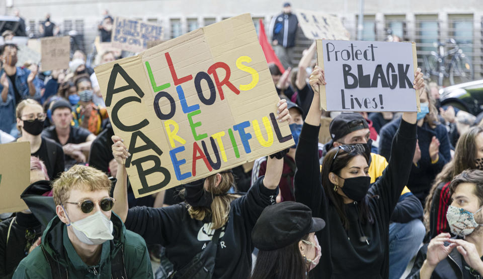 Demonstrators with posters attend a demonstration in Hamburg, Germany, Friday, June 5, 2020, to protest against the recent killing of George Floyd by police officers in Minneapolis, USA, that has led to protests in many countries and across the US. A US police officer has been charged with the death of George Floyd. (Markus Scholz/dpa via AP)