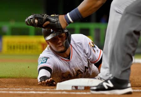 Jul 11, 2018; Miami, FL, USA; Miami Marlins shortstop Miguel Rojas (19) dives back to first base as Milwaukee Brewers first baseman Jesus Aguilar (24) is late with the tag in the fourth inning at Marlins Park. Mandatory Credit: Steve Mitchell-USA TODAY Sports