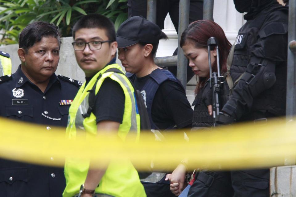 Indonesian suspect Siti Aisyah, second from right, in the ongoing assassination investigation, is escorted by police officers out from Sepang court in Sepang, Malaysia on Wednesday, March 1, 2017. Two women accused of smearing VX nerve agent on Kim Jong Nam, the estranged half brother of North Korea's leader, were charged with murder Wednesday after arriving in court under heavy protection. (AP Photo/Daniel Chan)