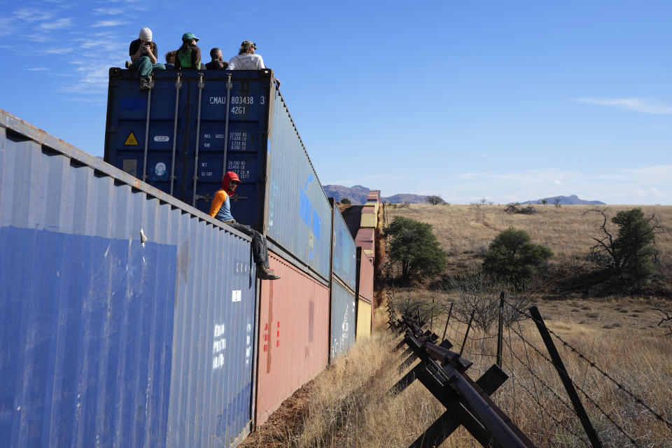 Activists sit on newly installed shipping containers along the border creating a wall between the United States and Mexico in San Rafael Valley, Ariz., Thursday, Dec. 8, 2022. Work crews are steadily erecting hundreds of double-stacked shipping containers along the rugged east end of Arizona’s boundary with Mexico as Republican Gov. Doug Ducey makes a bold show of border enforcement even as he prepares to step aside next month for Democratic Governor-elect Katie Hobbs. (AP Photo/Ross D. Franklin)
