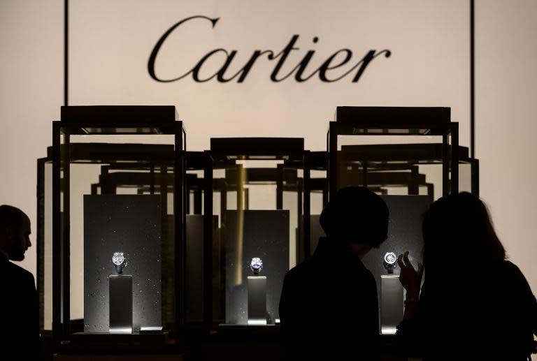 Visitors look at items on display at the stand of Cartier on the opening day of the "Salon International de la Haute Horlogerie", a professional fair in fine watchmaking, on January 19, 2015, in Geneva, Switzerland