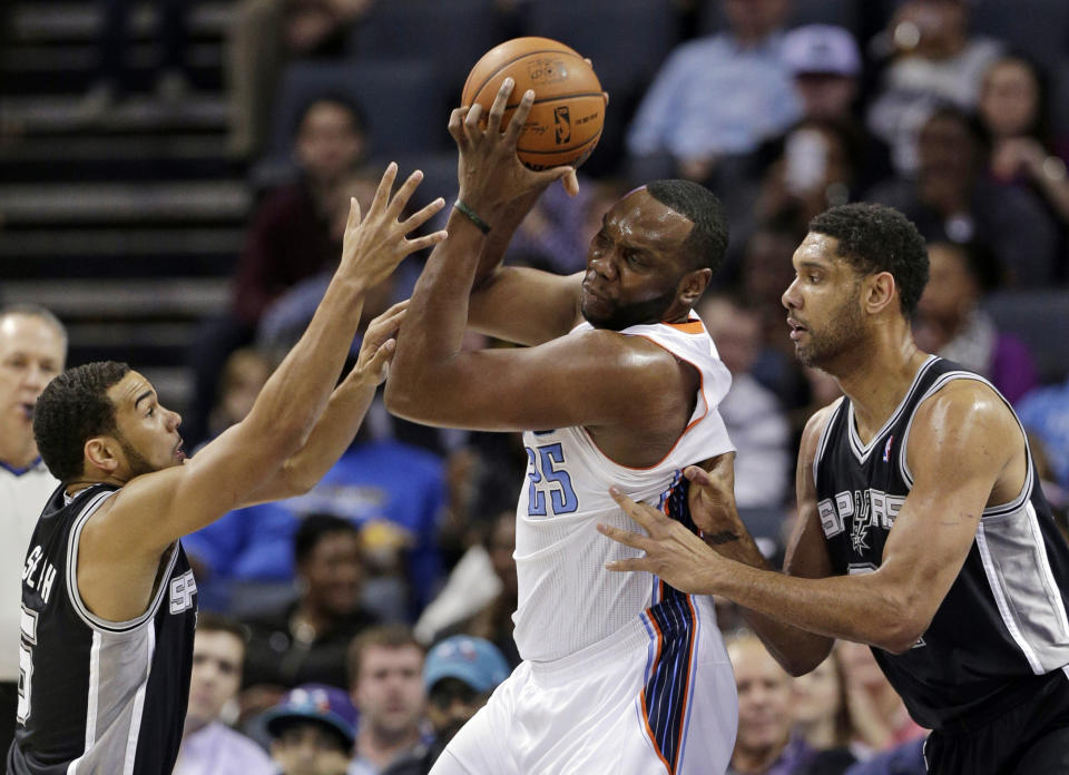 Charlotte Bobcats' Al Jefferson, center, is trapped by San Antonio Spurs' Tim Duncan, right, and Cory Joseph, left, during the first half of an NBA basketball game in Charlotte, N.C., Saturday, Feb. 8, 2014. (AP Photo/Chuck Burton)