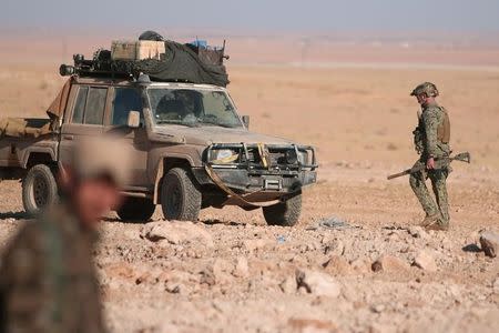 A U.S. fighter walks with his weapon near a military vehicle, north of Raqqa city, Syria November 6, 2016. REUTERS/Rodi Said/Files