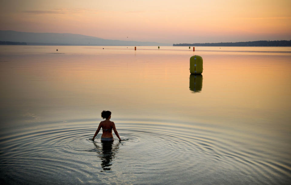 FILE - A woman takes a dip in Lake Geneva at sunrise in Geneva, Switzerland on Sunday, July 21, 2013. (AP Photo/Anja Niedringhaus, File)