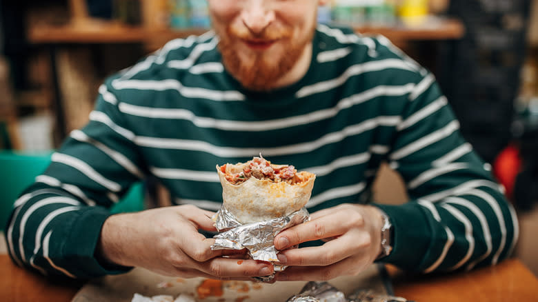man opens foil-wrapped burrito