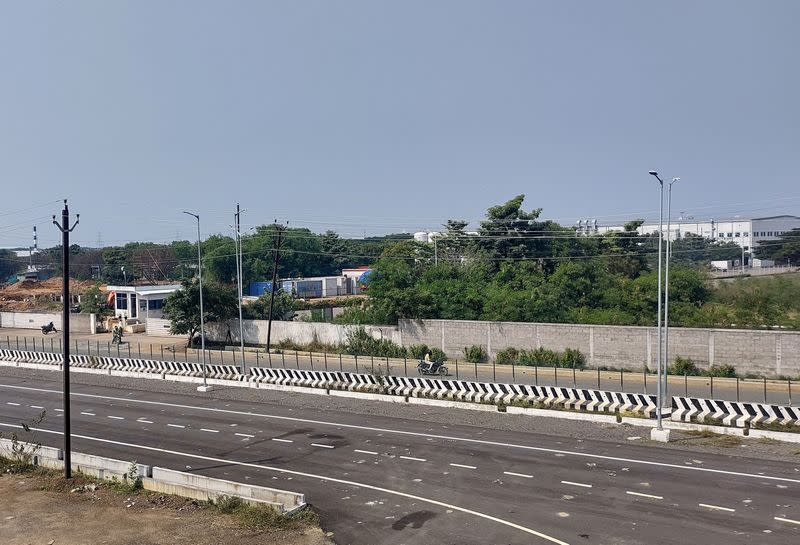 FILE PHOTO: Men ride their motorbikes past a closed plant of India Foxconn unit, near Chennai