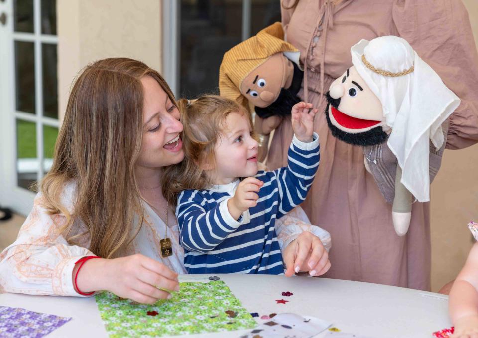 Sarah Dworcan and Manny Dworcan, 1, interact with Passover puppets during Tuesday's class.