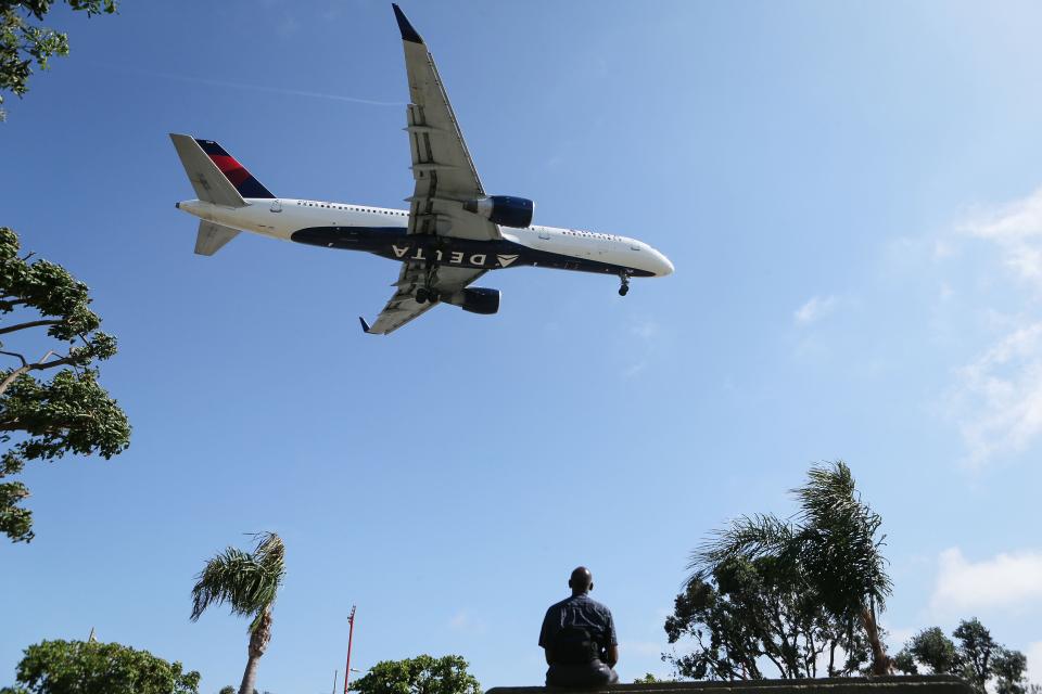 A man watches as a Delta Air Lines plane lands at Los Angeles International Airport on July 12, 2018 in Los Angeles, California. (Getty Images)