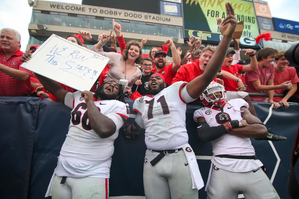 Georgia Bulldogs offensive lineman Solomon Kindley (66) and offensive lineman Andrew Thomas (71) and defensive back Ameer Speed (9) celebrate with fans after a victory against the Georgia Tech Yellow Jackets at Bobby Dodd Stadium on Nov. 30, 2019.