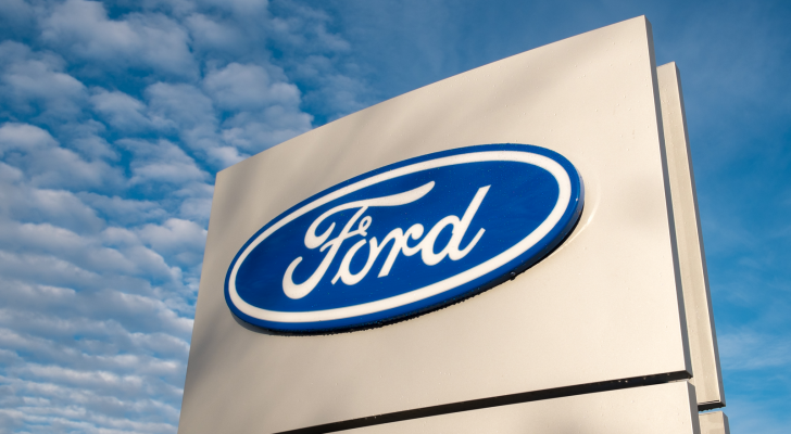 Ford (F) dealership sign against a blue sky.