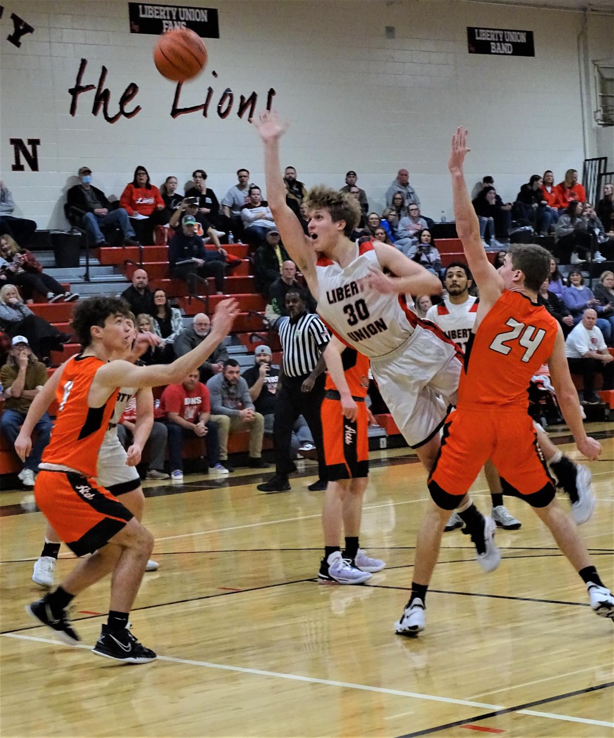 Liberty Union's Jacob Riddle lays in a shot between Amanda-Clearcreek defenders Jonny Weaver and Cade Young during the Lions' 52-47 Mid-State League-Buckeye Division win Saturday night.