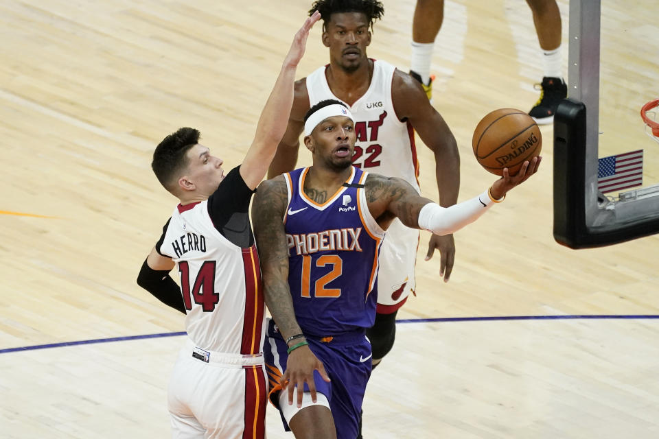 Phoenix Suns forward Torrey Craig (12) shoots past Miami Heat guard Tyler Herro (14) during the first half of an NBA basketball game, Tuesday, April 13, 2021, in Phoenix. (AP Photo/Matt York)