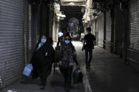 People walk through closed Tehran's Grand Bazaar, Iran, Saturday, April 10, 2021. Iran on Saturday imposed partial lockdown on businesses in major shopping centers as well as intercity travels through personal cars in major cities including capital Tehran as it struggles with the worst outbreak of the coronavirus in the Mideast region. (AP Photo/Vahid Salemi)