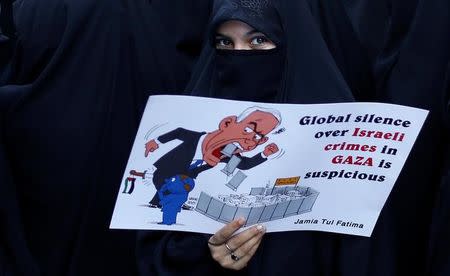 A veiled Muslim woman holds a placard during a protest, organised by various religious organisations, against the U.S. decision to recognise Jerusalem as the capital of Israel, in New Delhi, India, December 17, 2017. REUTERS/Adnan Abidi